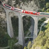 Viadukt, Felsen, Schlucht. Über die Brücke fährt ein Zug.