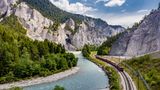 Fluss mit ausgewaschenen Tufffelsen. Neben dem Wasser verlaufen die Bahngleise.