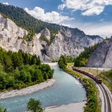 Fluss mit ausgewaschenen Tufffelsen. Neben dem Wasser verlaufen die Bahngleise.