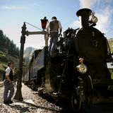 Dampflok beim Boxenstopp, zwei Männer beladen neue Kohle