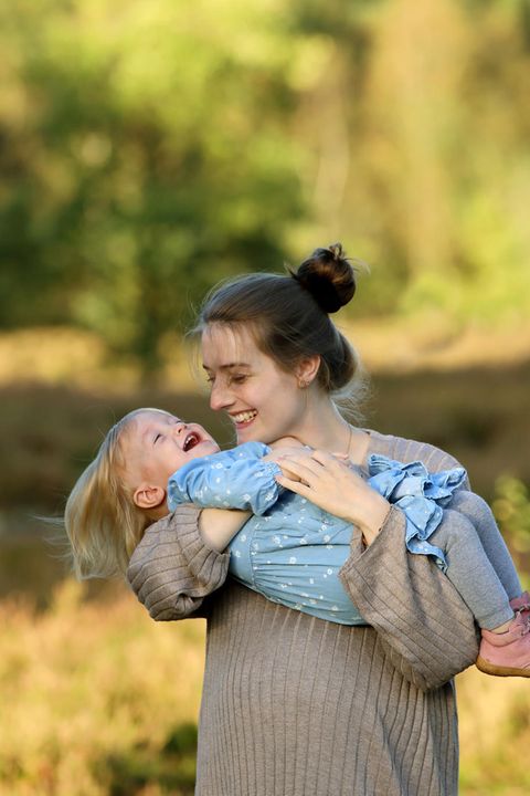 Eine junge Mutter hält ihre lachende Tochter auf dem Arm