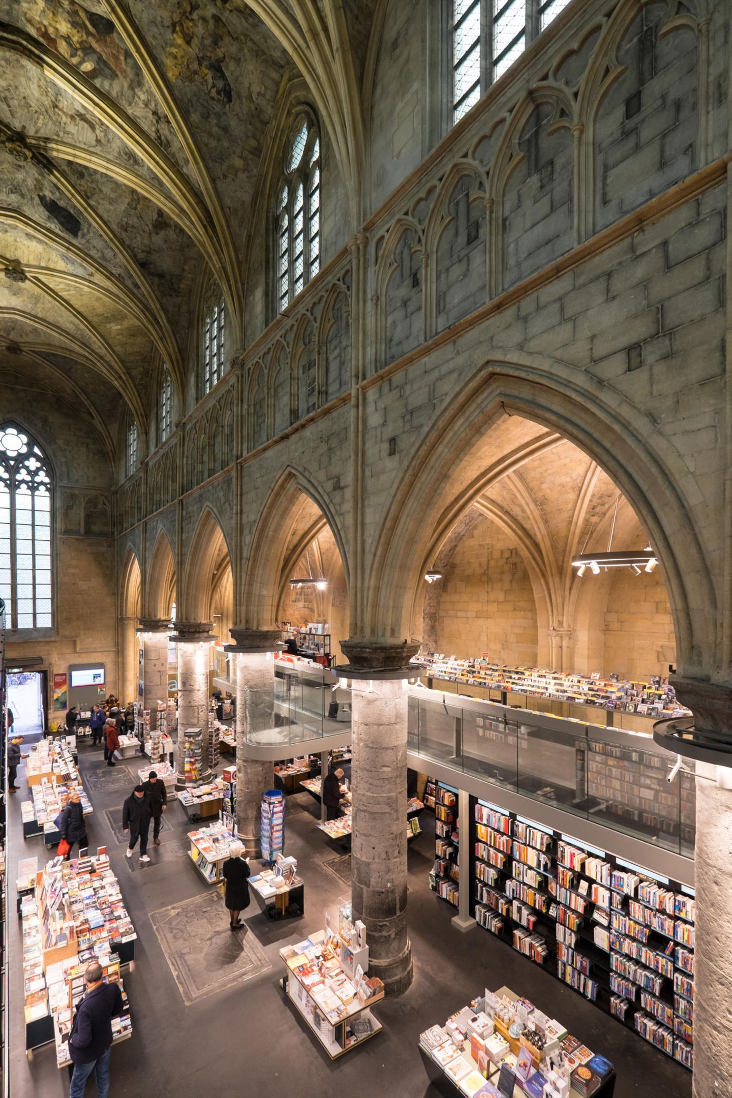 Interior of Dominican church converted into a bookstore with restaurant, customers, cathedral ceilings and pillars of the church in Maastricht, Netherland