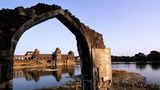Geisterstadt Mandu: Ein Blick durch einen gebrochenen Torbogen auf Wasser und Häuser