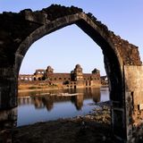 Geisterstadt Mandu: Ein Blick durch einen gebrochenen Torbogen auf Wasser und Häuser