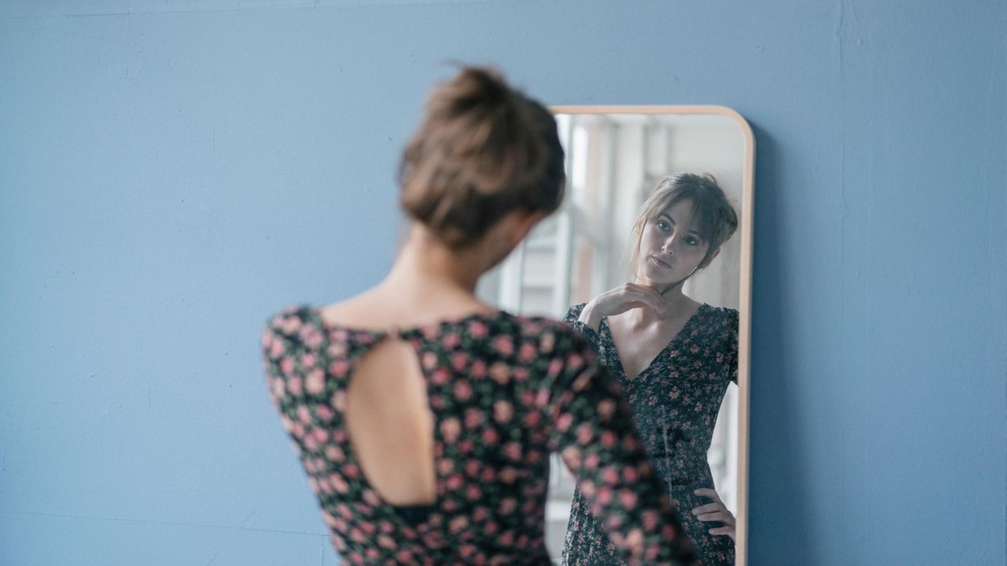 Eine junge Frau guckt sich selbst im Spiegel an  Eine junge Frau guckt sich selbst im Spiegel an
