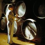 Mann steht in einer Bodega vor Fässern