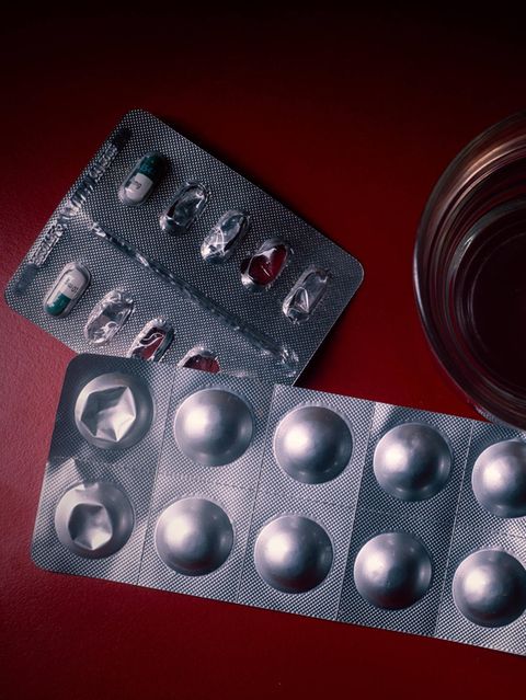 Angebrochene Tablettenblister und Wasserglas