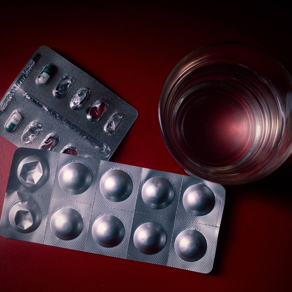 Angebrochene Tablettenblister und Wasserglas