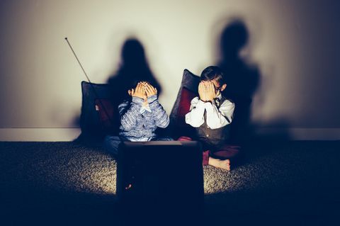 Zwei Jungen halten sich die Augen zu, während sie fernsehen