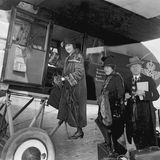 Zwei Frauen und ein Mann in eleganter Kleidung beim Einsteigen in eine Propellermaschine