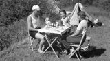 Drei Leute sitzen um einen Tisch beim Campen