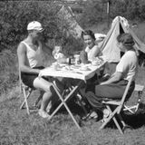 Drei Leute sitzen um einen Tisch beim Campen