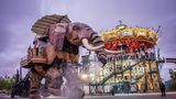 Beleuchtetes Karussell mit Meerestieren, auf dem Platz davor übergroßer künstlicher Elefant, Abendstimmung