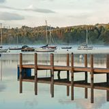 Ein Steg im Nebel mit Booten im Hintergrund