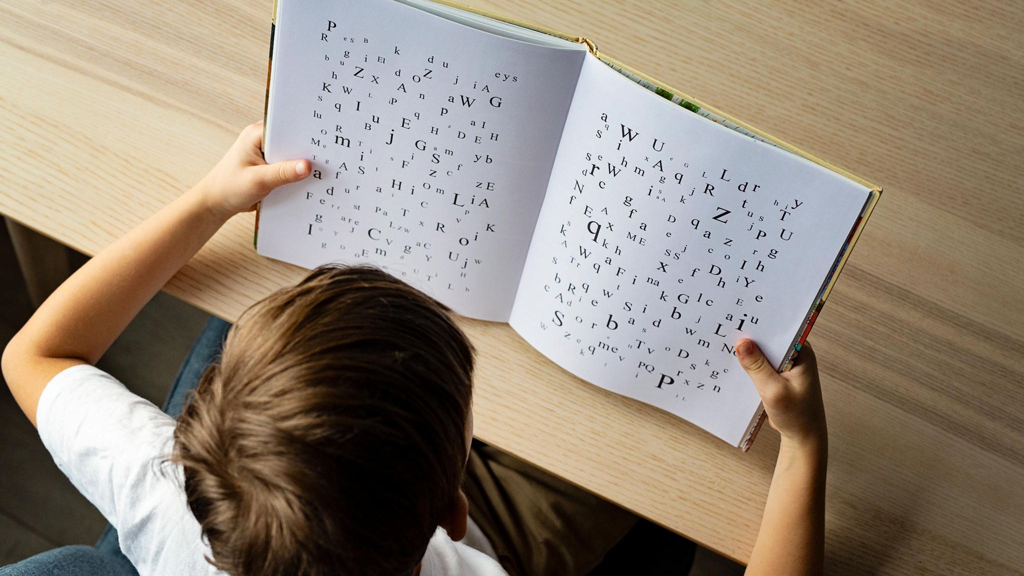 Ein Kind schaut in ein Buch mit Buchstaben
