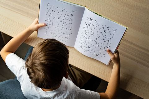Ein Kind schaut in ein Buch mit Buchstaben