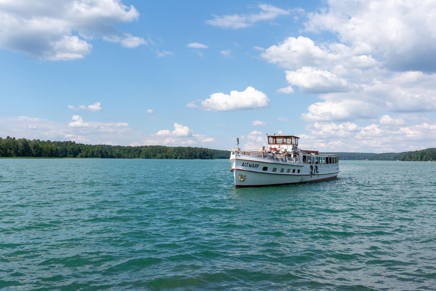 Werbellinsee: Schiffchenfahren und Abtauchen Seefläche mit Dampfer, dahinter am Ufer Wald