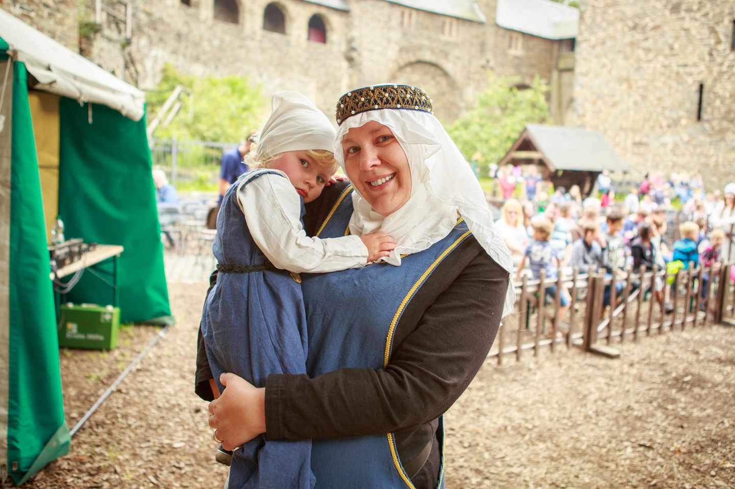 Ritterspiele auf Schloss Burg eine Frau trägt ein kleines Mädchen, beide tragen Kostüme