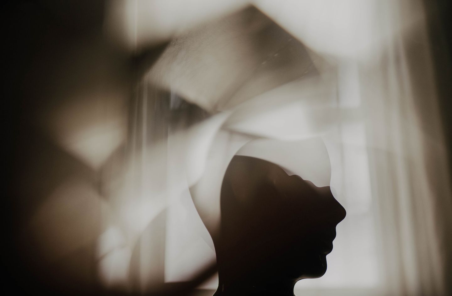 Silhouette eines Kopfes mit prismatischen Bildelementen vor einem Fenster. Silhouette eines Kopfes mit prismatischen Bildelementen vor einem Fenster.
