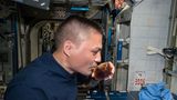 Astronaut trinkt Kaffee aus einer seltsam geformten Tasse