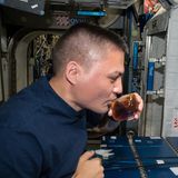 Astronaut trinkt Kaffee aus einer seltsam geformten Tasse