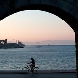 Rhodos, Griechenland - Blick auf die Hafeneinfahrt mit Radfahrerin im Vordergrund