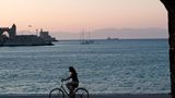 Rhodos, Griechenland - Blick auf die Hafeneinfahrt mit Radfahrerin im Vordergrund