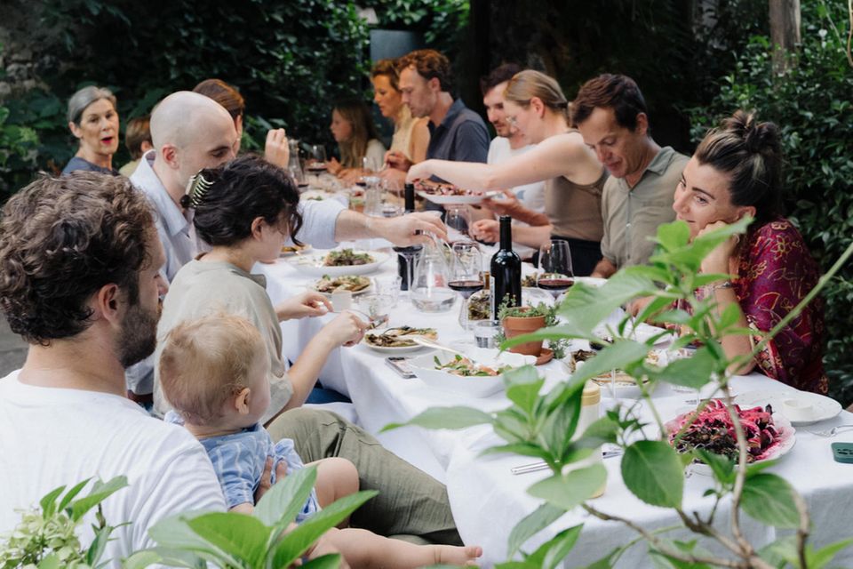 Menschen essen zusammen an einem reich gedeckten Tisch im Grünen