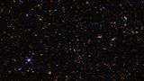 Foto des Alls mit viel Dunkler Fläche und vereinzelten Sternen und Galaxien