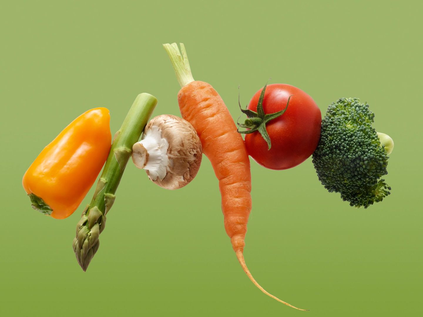 Verschiedene Gemüssorten vor grünem Hintergrund: Paprika, Spargel, Champignong, Karotte, Tomate, Brokkoli