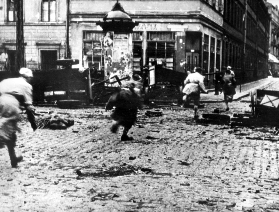 Menschen flüchten 1944 über eine kriegszerstörte Straße in Warschau Menschen flüchten 1944 über eine kriegszerstörte Straße in Warschau
