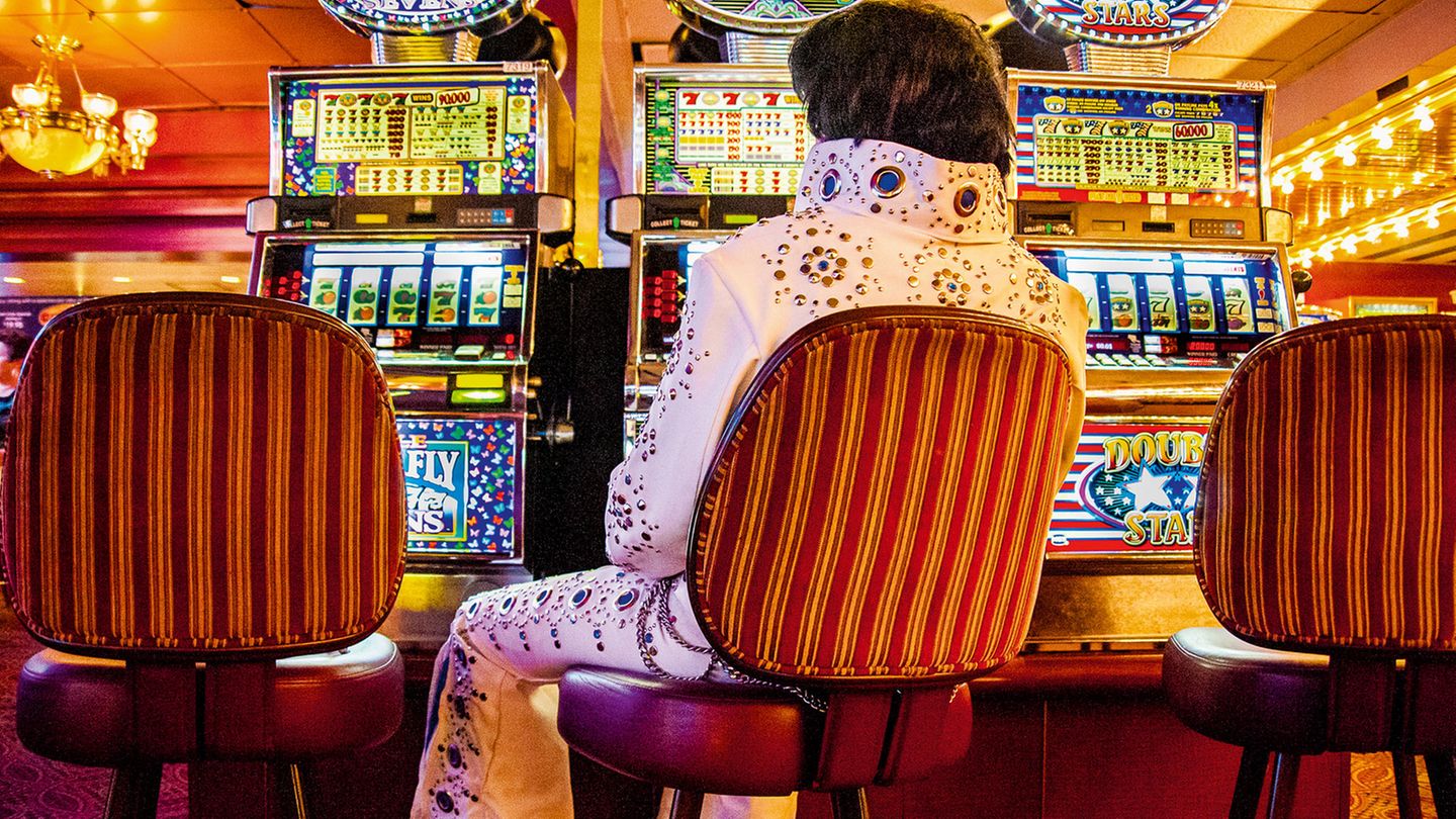 Ein Mann im Elvis-Kostüm sitzt allein vor einer Reihe Spielautomaten