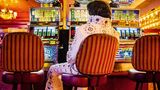 Ein Mann im Elvis-Kostüm sitzt allein vor einer Reihe Spielautomaten