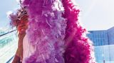 Frau im Showkostüm, mit gewaltigen pinkfarbigen Federboas auf dem Kopf