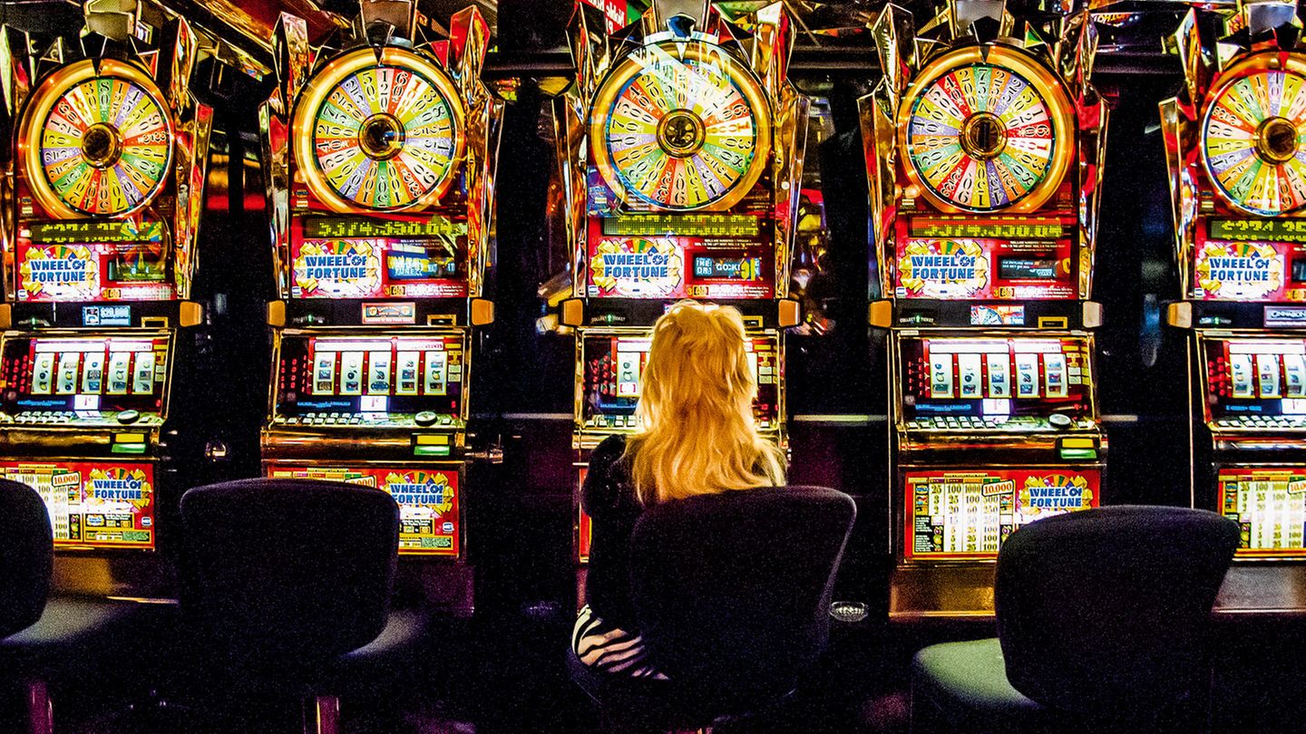 Eine Frau mit hellen, langen Haaren sitzt vor einer Reihe identischer Spielautomaten