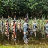 Viele militärisch anmutende Statuen, die halb im Wasser versunken sind