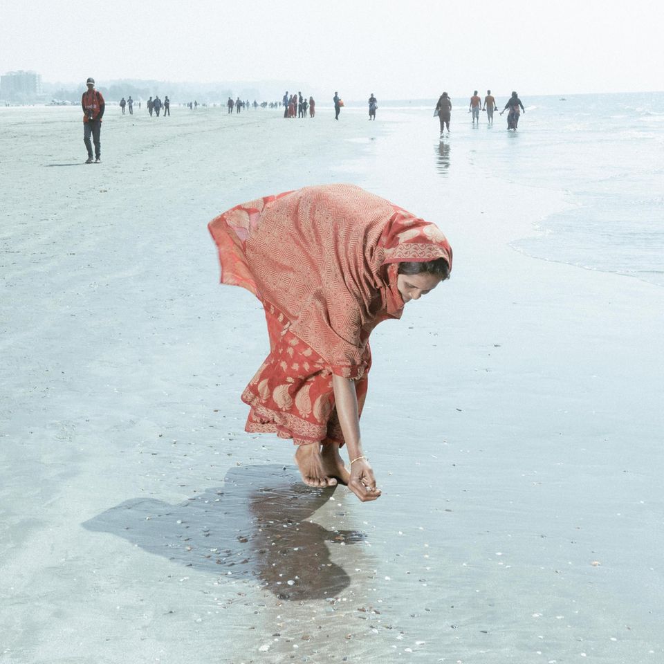 Frau am Strand sammelt Muscheln