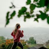 Junge, blonde Frau joggt vor Züricher Stadtpanorama im Hintergrund