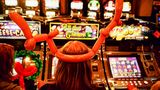 Eine Frau mit einem Geweih aus Luftballon sitzt vor Glücksspielautomaten