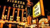 Front des Pioneer Clubs mit Leuchtreklame in Form eine rauchenden Cowboys bei Nacht