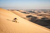 Jemand beim Sandboarden im Sand von Peru