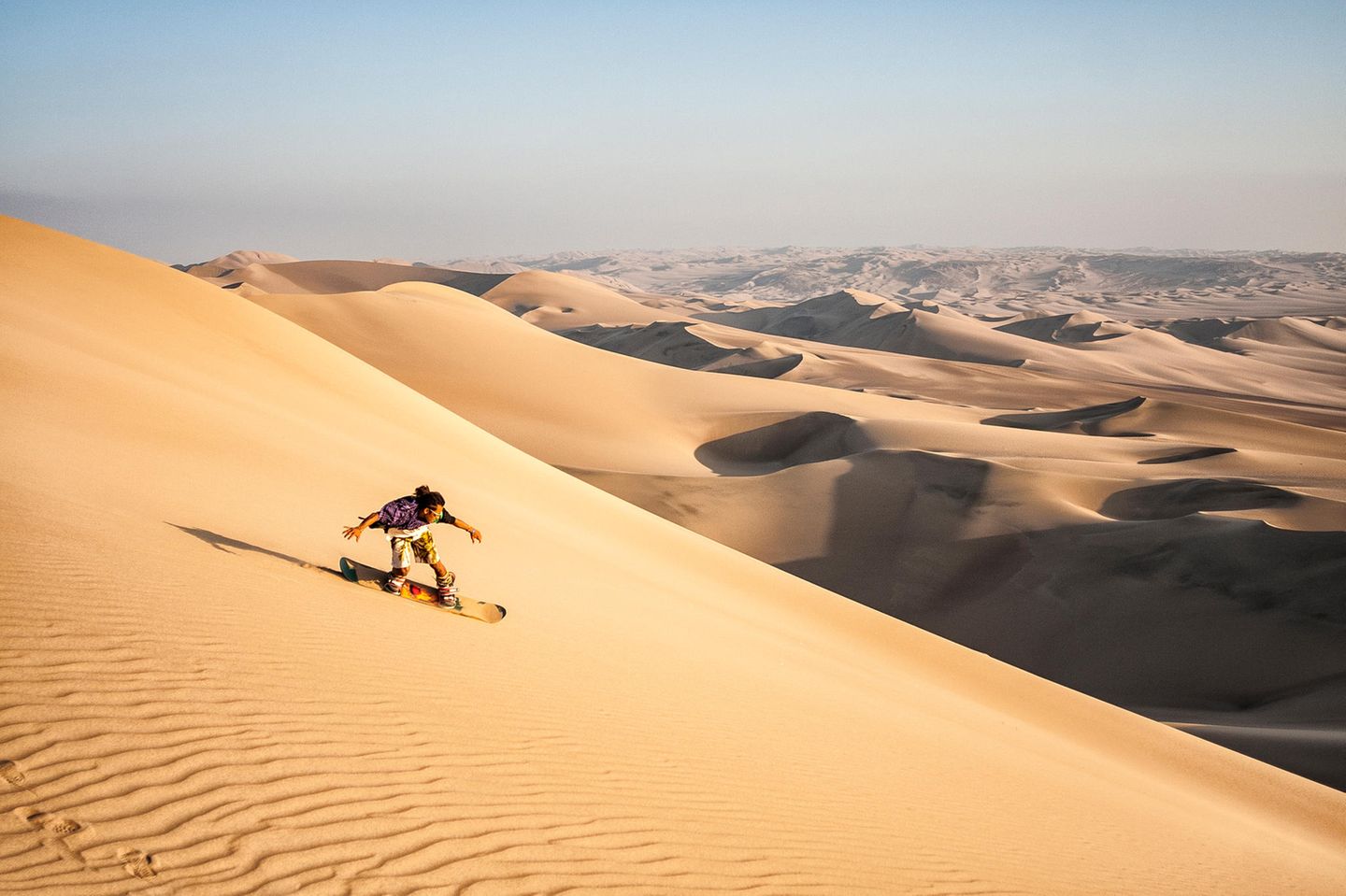 Peru: Sandboarding in der Wüste  Jemand beim Sandboarden im Sand von Peru