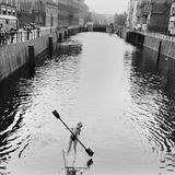 Ein Junge paddelt auf einem Holzfloß über einen Kanal in Berlin
