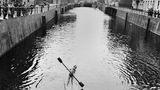 Ein Junge paddelt auf einem Holzfloß über einen Kanal in Berlin