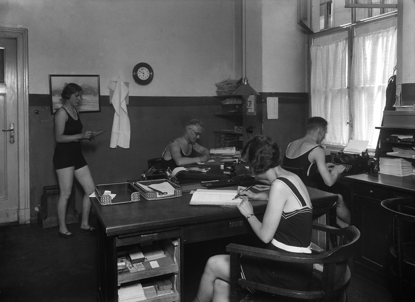 In einem Büro arbeiten Männer und Frauen in Badeanzügen