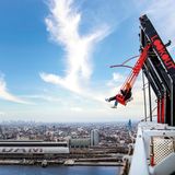 Menschen schwingen sich over the edge von Amsterdam, dahinter ist ein Blick auf die Stadt zu sehen