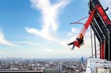 Menschen schwingen sich over the edge von Amsterdam, dahinter ist ein Blick auf die Stadt zu sehen