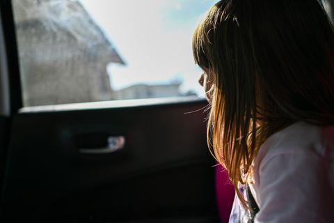 ein kleines Mädchen, das aus dem Autofenster schaut und in die Sonne schaut