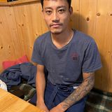 Mann sitzt am Tisch, Tattoos auf dem Arm