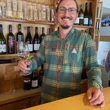 Lächelnder Mann an der Bar mit Weinglas